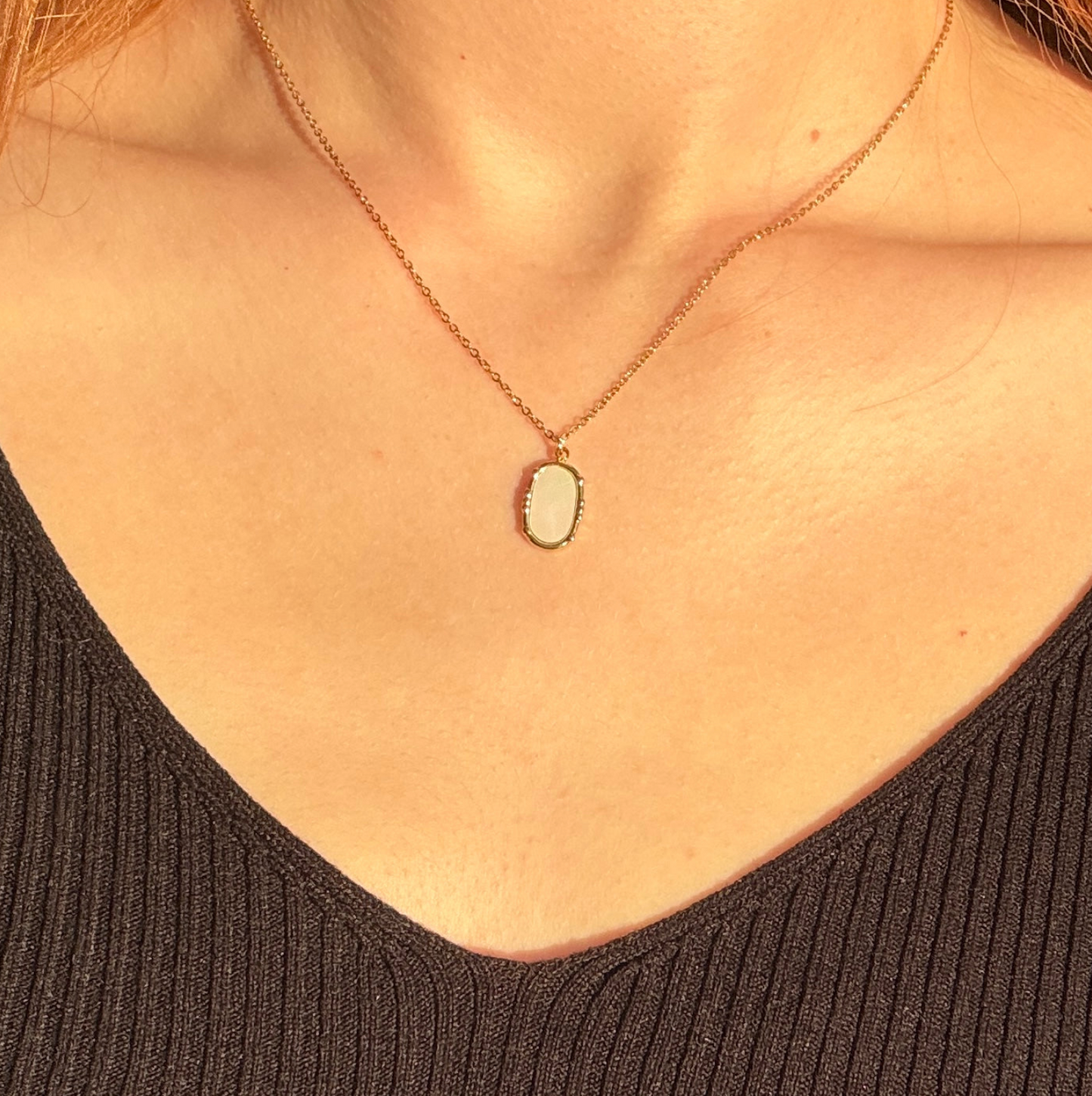 Necklace with a pendant on a person wearing a black top